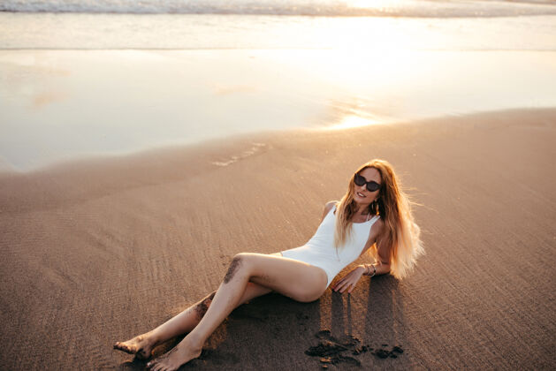 海洋迷人的白种女人戴着时髦的耳环在沙滩上摆姿势度假灵感阳光美丽