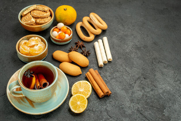 小吃前视图一杯茶加糖果饼干和水果放在灰色的茶几上甜甜的饼干水果饼干茶