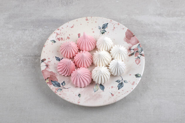 蛋白酥皮粉色和白色的蛋白酥皮放在盘子里 放在大理石桌上糕点卡路里甜点