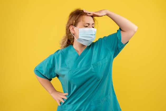 绝育黄色墙壁上穿着医疗服 戴着无菌口罩的年轻女医生的正视图美女医院正面