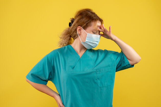 面具黄墙上年轻女医生穿着医疗服 戴着口罩的正面图正面年轻女医生人