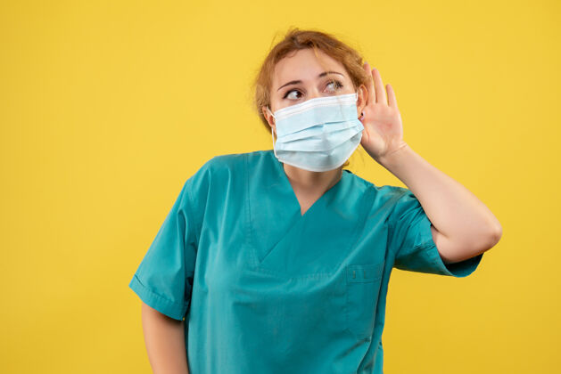 面具黄墙上年轻女医生穿着医疗服 戴着口罩的正面图肖像医疗前面