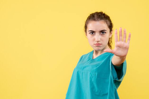 情绪黄色墙上穿着医用衬衫的年轻女医生的正视图健康医院自信