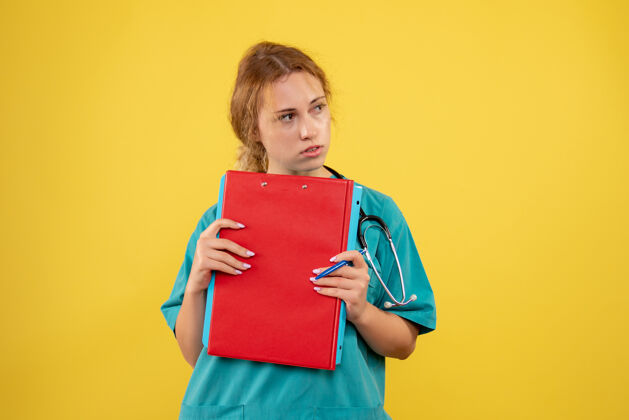 人黄色墙壁上穿着医疗服的女医生拿着纸和分析的正视图漂亮快乐医疗