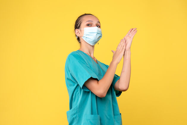 女医生黄墙上穿着医疗服 戴着无菌口罩的女医生的正面图护士绝育病毒