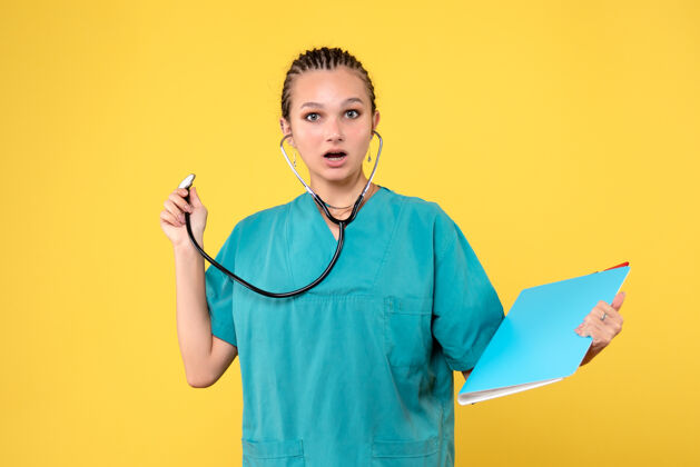 医院女医生穿着医用套装 手持听诊器 黄色墙壁上的分析情绪健康医疗