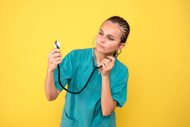 前面黄色墙壁上穿着带听诊器的医用衬衫的女医生的正视图医生医疗药品