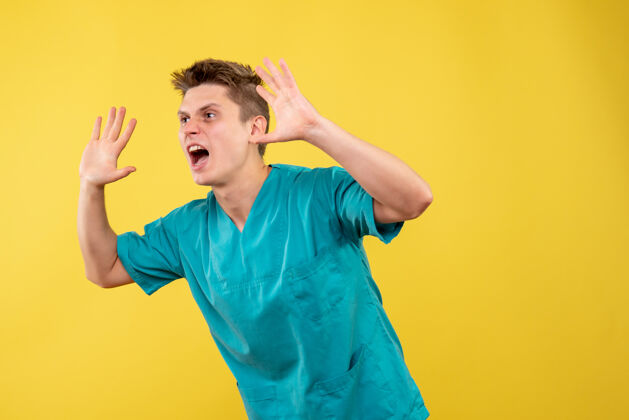 医学身穿医疗服的男医生在黄色墙上尖叫的正视图男医生成人前面