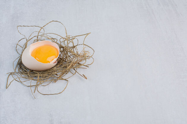 营养蛋黄在蛋壳上放一小堆稻草在大理石桌上农产品早餐蛋壳