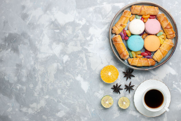 桌子顶视图甜百吉饼加麦卡龙和一杯白茶饼干咖啡盘子