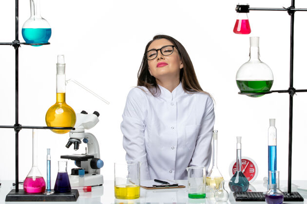 成人前视图穿着白色医疗服的女化学家坐在白色背景上解决科学病毒实验室病毒大流行西装微笑家庭主妇