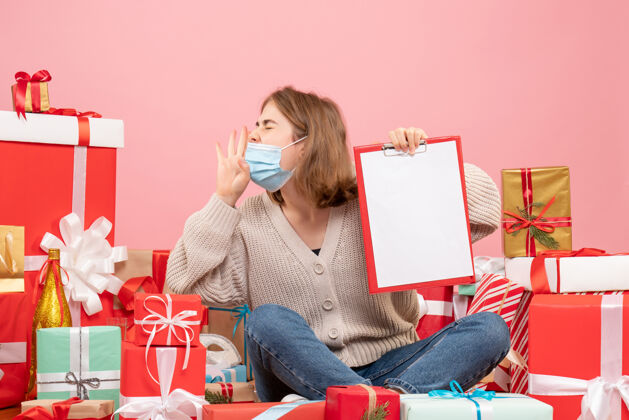 病毒前视图年轻女性坐在圣诞礼物面具与注意年轻女性情绪礼物