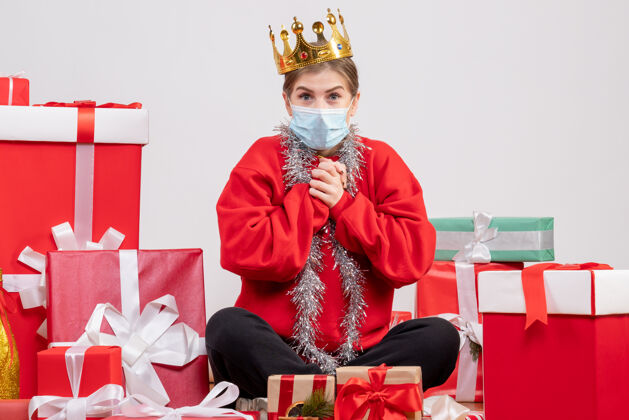 人正面图年轻女性戴着面具和皇冠坐在那里 手里拿着圣诞礼物礼物年轻女性面具