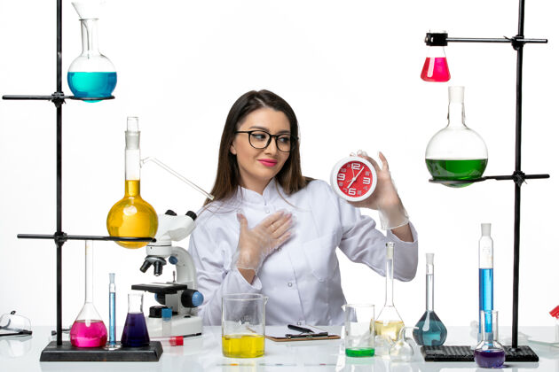 前面前视图穿着白色医疗服的女化学家拿着红色时钟站在白色背景上科学病毒冠状病毒-大流行实验室专业罐子科学