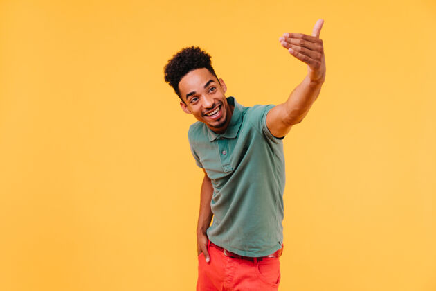 自信一个穿着考究的黑人 留着一头短发 情绪化地摆着姿势穿着绿色t恤的快乐男人的肖像男性男孩积极
