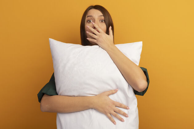漂亮惊艳的白种女人抱着枕头 把手放在橘子上的嘴上枕头时尚漂亮