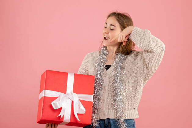 情绪正面图年轻女性手持圣诞礼物举行时尚粉色