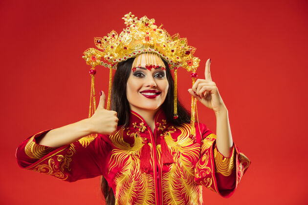 东方中国传统的优雅女子在红色背景的工作室里微笑穿着女性