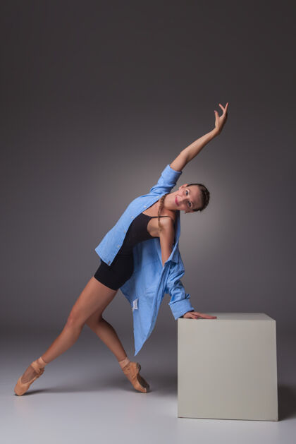 感性年轻漂亮的现代风格舞蹈演员在白色立方体上摆姿势 背景是灰色的工作室身体年轻移动
