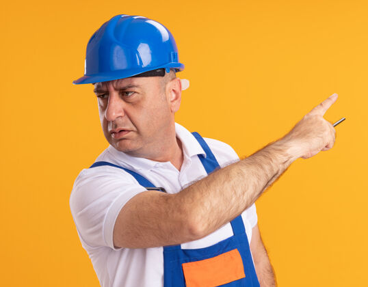 建设者一个穿着制服的白人成年建筑工人拿着铅笔 指着橙色的边人壁板尖