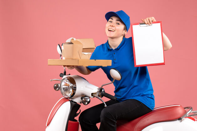 文件正面图：女快递员带着食品包装和文件说明上粉红色的工作色工人送食品自行车制服服务颜色摩托车制服
