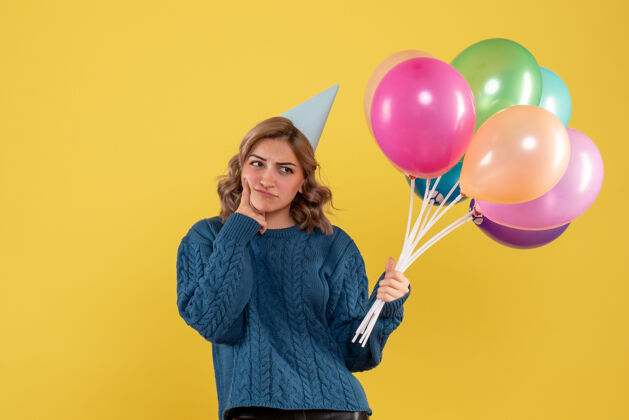 庆祝正面是年轻女性 带着五颜六色的气球和思考年轻女性颜色聚会