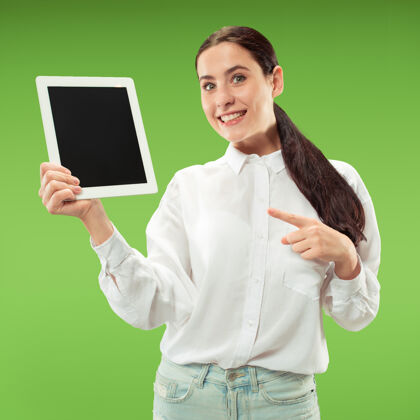 年轻人一个自信的休闲女孩的肖像 显示绿色背景下笔记本电脑的空白屏幕个人智能女孩