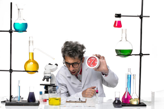 烧杯前视图身穿医疗服的男科学家手持白色背景上的红色时钟化学冠状病毒实验室健康容器实验室化学