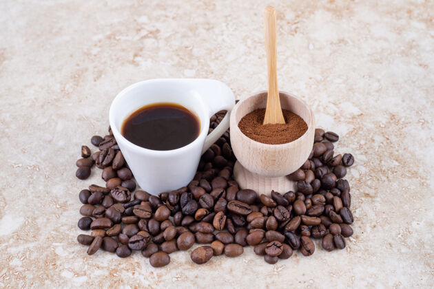 豆一小碗磨碎的咖啡粉和一杯放在一堆咖啡豆上的咖啡地美味碗
