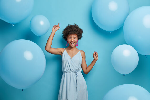 情感乐观开朗的喜庆女人 带着好莱坞的微笑 欢笑出欢乐 随着音乐悠闲地移动和跳舞 玩得开心 拍快乐的节日照片 庆祝周年纪念 被气球包围年轻卷发气球