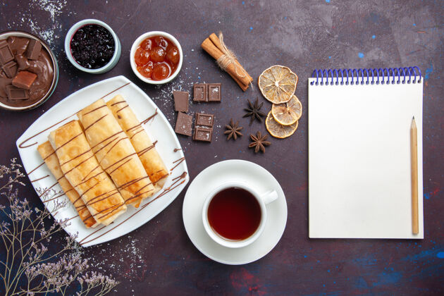 美味在黑暗的桌子上俯瞰美味的甜点和巧克力果酱以及一杯茶甜点热的咖啡