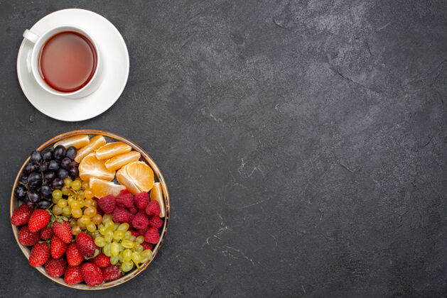 咖啡顶视图水果成分草莓葡萄覆盆子和橘子茶在黑暗的桌子上橘子覆盆子成分