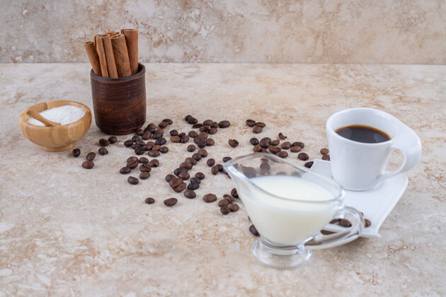 肉桂一小碗糖和肉桂棒在一个木杯旁边散落的咖啡豆 提供一杯牛奶和一杯咖啡干棒芳香