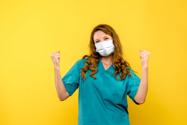 医学黄色墙壁上戴着面具的女医生的正视图职业正面衬衫