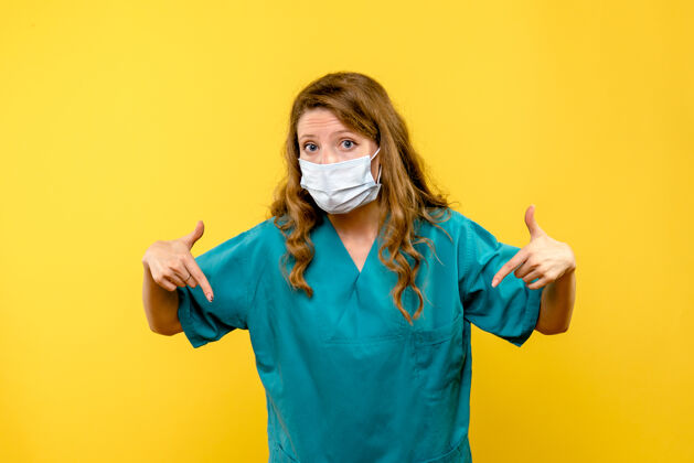 漂亮黄色地板上戴着面罩的女医生的正面图医疗保健病毒-大流行面具微笑黑发