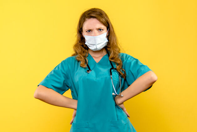 女人黄墙上戴着面具的女医生的正视图女医生脸支持