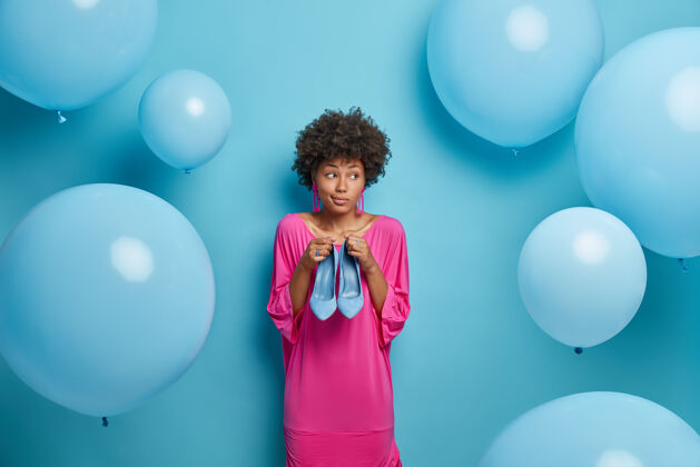 女人沉思的优柔寡断的女人想什么穿在脚上合身的衣服 拿着高跟蓝鞋 为生日聚会穿的衣服 穿着花哨的粉色长裙 隔着墙 气球精品时尚请