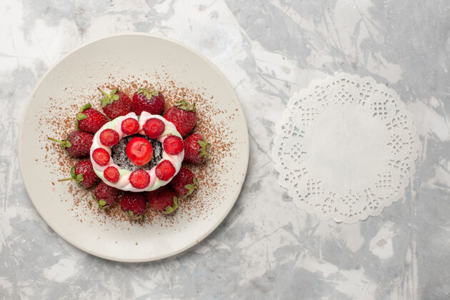 生的白色桌面上有新鲜的红色草莓和蛋糕瓷器容器顶部