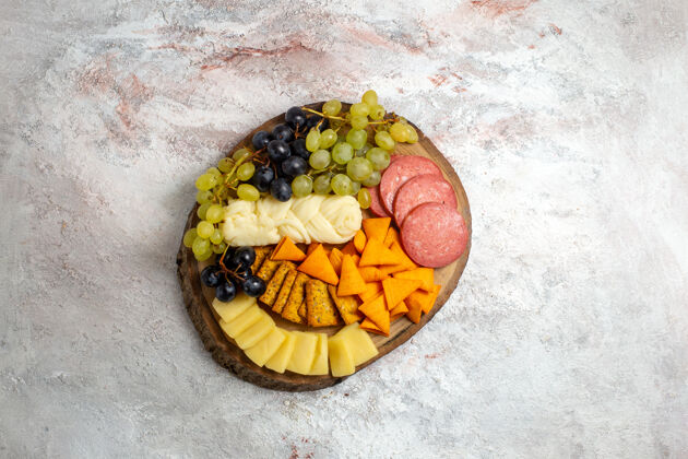 新鲜顶视图不同的小吃cips香肠奶酪和新鲜葡萄在一个空白的空间盘子葡萄香肠