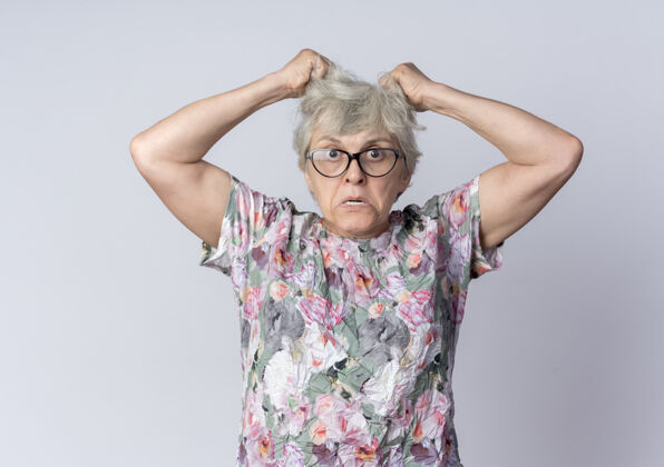 老年人愤怒的老妇人戴着眼镜 举着头发 看起来像是隔离在白墙上举眼镜女人