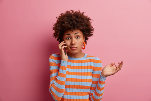 电话被质问的美国黑人妇女的画像有电话交谈和回答犹豫 做了权衡的手势和怀疑的举手 不知道和不知道 不确定室内青年困惑