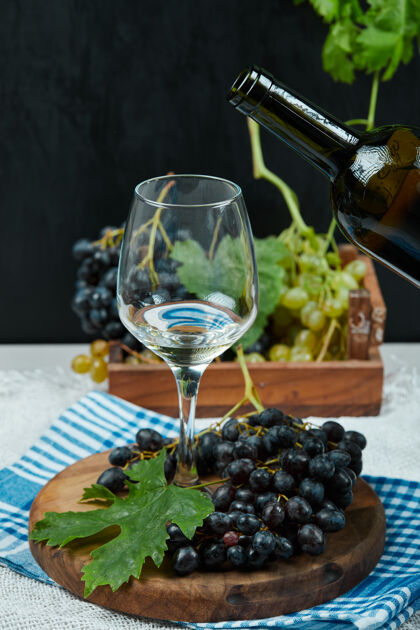 瓶子一盘葡萄和一杯葡萄酒放在白色的桌子上 配上酒瓶高质量的照片水果成熟杯子