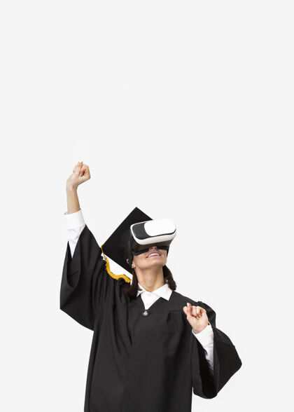 虚拟现实模拟器穿着毕业礼服戴毕业帽戴着虚拟现实耳机的女人毕业毕业帽技术