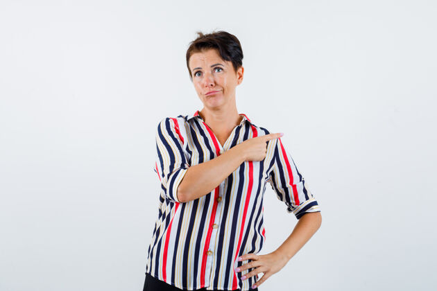 活跃成熟的女人手放在腰上 穿着条纹衬衫指着身后 表情严肃 前视条纹老年腰