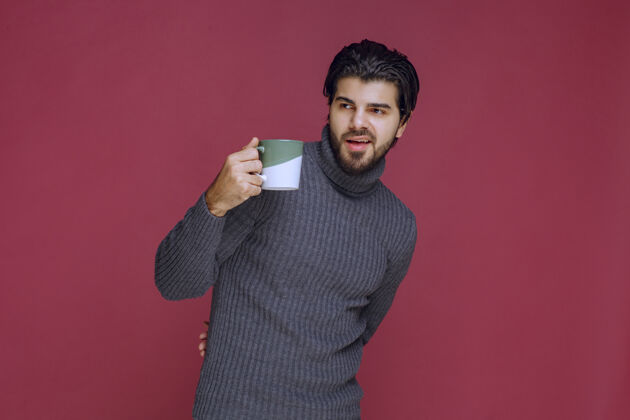 工人一个穿着灰色毛衣的男人手里拿着一个咖啡杯员工聪明休闲