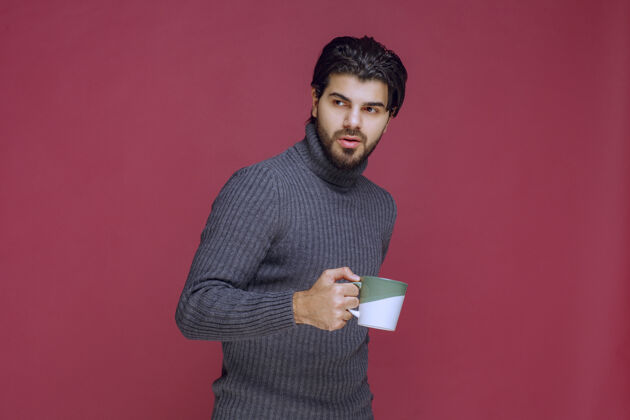 模特一个穿着灰色毛衣的男人手里拿着一个咖啡杯茶年轻人工人