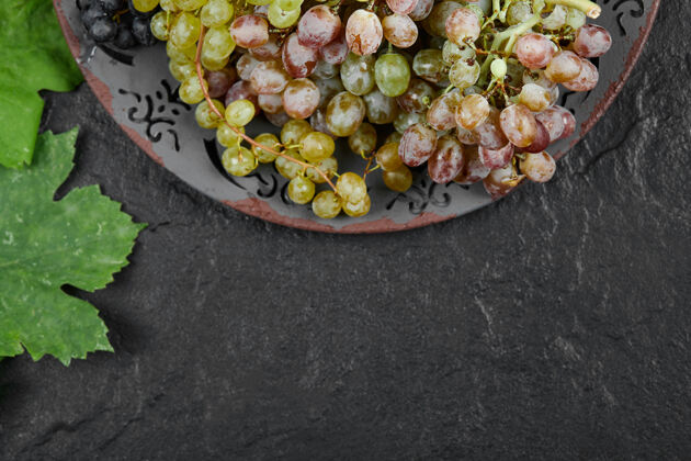 食品一盘深色背景上有叶子的混合葡萄高质量的照片串葡萄膳食