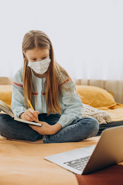 孩子在校女生戴着口罩在家学习 远程学习家庭学校笔记本电脑留在家里