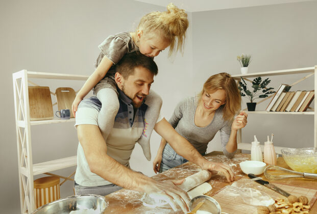 父亲可爱的小女孩和她美丽的父母在家里的厨房里准备蛋糕家庭生活方式的概念厨房周末晚餐