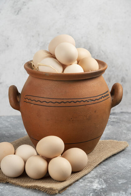 天然装满生鸡蛋的泥锅放在大理石上鸡蛋食品有机